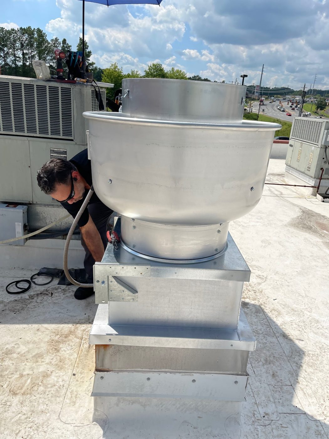 Technician servicing a rooftop exhaust fan